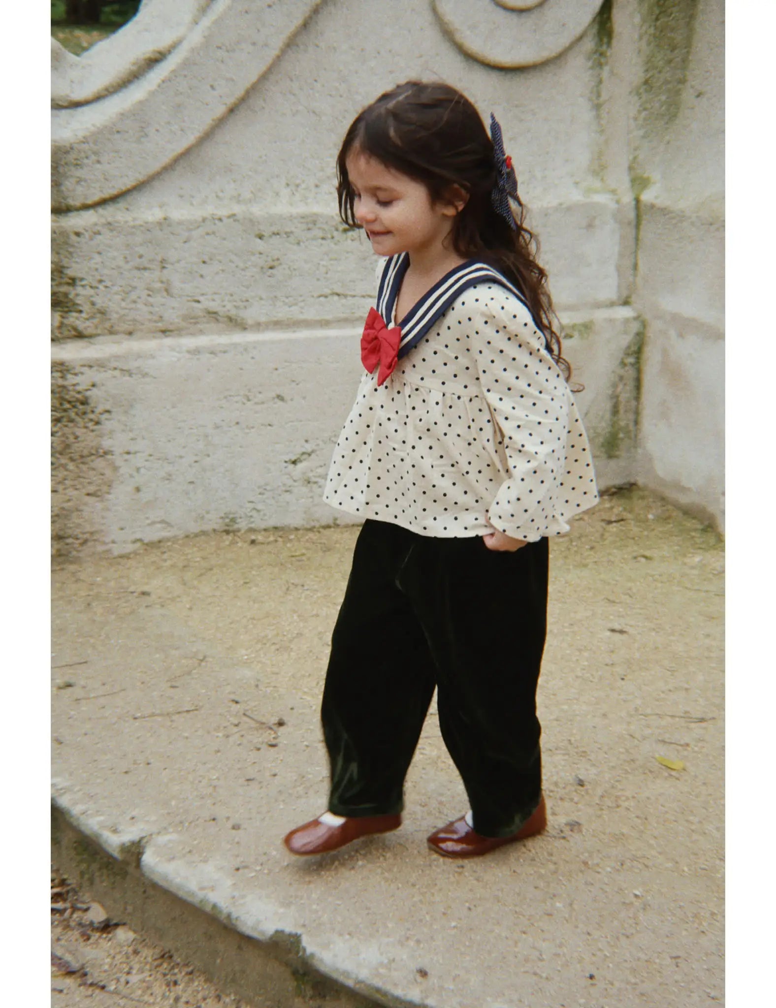 Camisa infantil creme com bolinhas pretas e gola azul-marinho, laço vermelho. Konges Sløjd
